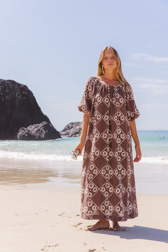 Dahlia Maxi Dress Maple — full length beach styling with rocky headland, on-shoulder neckline option, hand block print linen in maple brown | Daughters of India