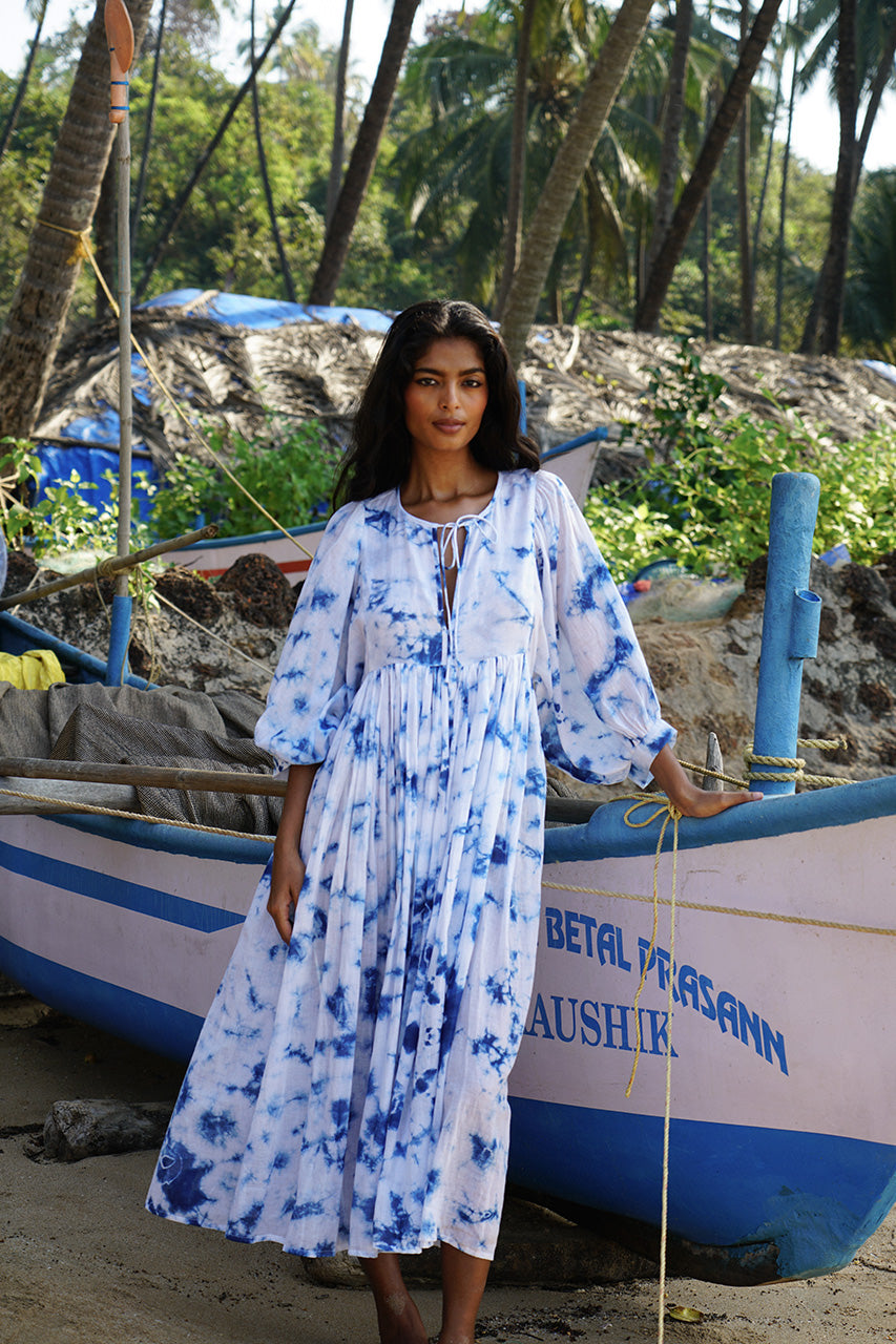 Kyra Midi Dress Deep Sea — close-up upper body showing V-neckline tie and balloon sleeve detail, deep sea shibori tie-dye cotton, beach setting | Daughters of India